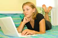 girl on bed with computer in community colleges with dorms
