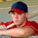 Baseball player in dugout representing college baseball camps and showcases