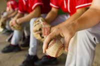 Baseball players sitting on bench representing NCAA D1 baseball colleges