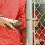 coach with scorebook representing questions to ask college coaches