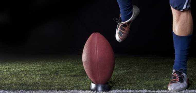 foot kicking a football representing how to start college athletic recruiting process