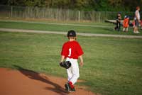 Little League player walking off field representing baseball ends