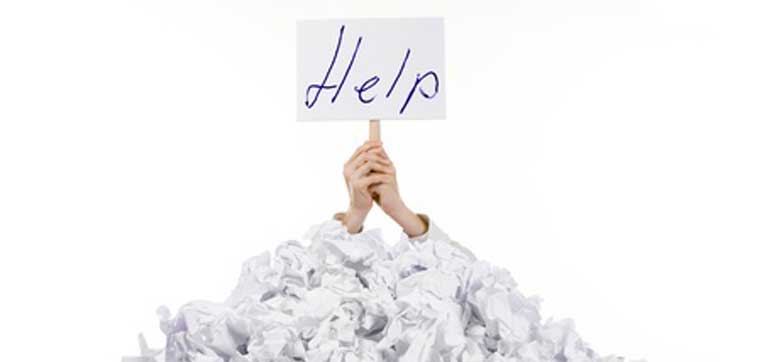 hands with help sign in piles of paper representing need for fafsa preparers