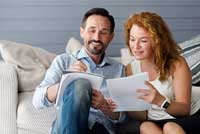 couple sitting on sofa reading about the 7 ways to compare colleges